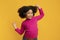 Positive funny african american girl wearing wireless headphones and dancing