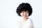 A positive funny Korean Asian woman with a smile in an Afro wig on a white background in the studio.