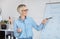 Positive German teacher explaining foreign language rules near blackboard indoors, panorama