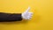 Positive gestures. A male\'s hand in a shirt and white glove shows a thumbs-up gesture. Close up. Yellow background