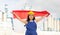 Positive girl in overalls with the Indonesia flag in her hands against the background of chimneys of modern factory