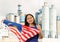 Positive girl in overalls with Malaysia flag in her hands against the background of chimneys of modern factory