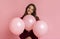 Positive girl posing with three rosy baloons, standing over pink background