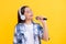 positive girl singing into music microphone isolated on yellow. teenage singer girl singing music on background. singer