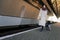 Positive girl with suitcase walks on the platform of the railway station near train car.