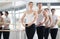 Positive girl with women and men engaged in group class perform exercise near ballet barre