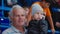 Positive grandfather holds little boy watching hockey game