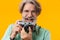 Positive grey-haired man photographer holding camera