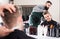 positive guy stylist creating haircut for man client at hairdressing salon