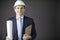 Positive handsome constructor in helmet formal clothing holds drawing smiling