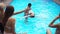 Positive handsome Middle Eastern man helping Caucasian slim attractive woman learning to swim in pool. Blurred female