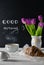 Positive and happy breakfast setting with tulips bouquest, coffee and croissant. Good morning