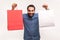 Positive happy man in blue shirt showing two paper bag looking at camera with toothy smile, successful shopping