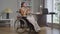 Positive happy smiling disabled woman in wheelchair looking away drinking coffee in the morning in home office. Wide