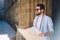 Positive hipster guy in casual wear resting on old stairs during sightseeing tour in city