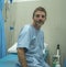 Positive and hopeful hospital patient smiling before adversity - young attractive and trustful man sitting on clinic bed