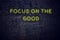 Positive inspiring quote on neon sign against brick wall focus on the good