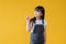 A positive little Asian girl in a cute jeans dress is looking and pointing her finger aside