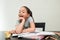 Positive little girl doing homework at home looking a sweet apple. School girl rests her head on her hand on a white background