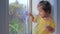 Positive little girl draws on the window. Kid at home concept. Quarantine