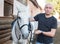 Positive male farmer standing with white horse at stable