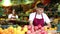 Positive man store employee displaying assortment of oranges at fruit department in supermarket