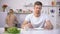 Positive man waiting for dinner, young wife cooking soup on background, hunger