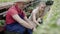 Positive man and woman sitting in greenhouse and talking. Mid-adult Caucasian male worker and young female biologist