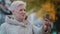 Positive mature grandmother make video call waving hello older granny enjoy nice virtual conversation in autumn park