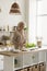 Positive mature lady cooking pastry sweet food in home kitchen