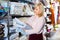 Positive mature woman choosing cotton bedcover in the textile shop