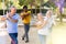 Positive mature women and men practicing vigorous dance movements in summer park