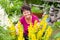 Positive middle-aged woman sitting among flowers in a summer garden