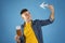 Positive millennial guy with paper plane, tickets and international passport on blue studio background