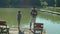 Positive multiethnic family with fishing rods angling on pond from jetty