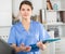 Positive nurse with folder of documents at clinic office