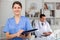 Positive nurse with folder of documents at office