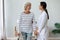 Positive old lady with walker talk with caring nurse