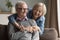 Positive older retired couple in love hugging on sofa