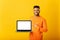 Positive optimistic indian guy freelancer or student showing laptop with empty screen and points finger on it