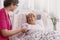 Positive patient lying in hospital bed with helpful nurse in pink uniform at her site