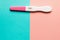 Positive pink plastic pregnancy test on pink and blue background