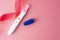 Positive platic pregnancy test isolated on pink background, copy space