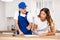 Positive plumber tells an young housewife where to sign an invoice for work performed.