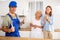 Positive plumber in uniform against of two satisfied female customers in the kitchen at home