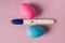 A positive pregnancy test on a pink background and pink and blue eggs, determining the gender of the unborn child.