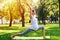 Positive pregnant woman meditating in yoga pose outdoors