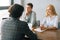 Positive professional young woman and man headhunters holding interview with unrecognizable male job seeker wearing suit