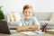 Positive redhead boy schooler doing homework at home