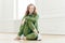 Positive redhead fitness girl feels relaxed, wears tracksuit, sportshoes, has rest after yoga training indoor, poses on floor,